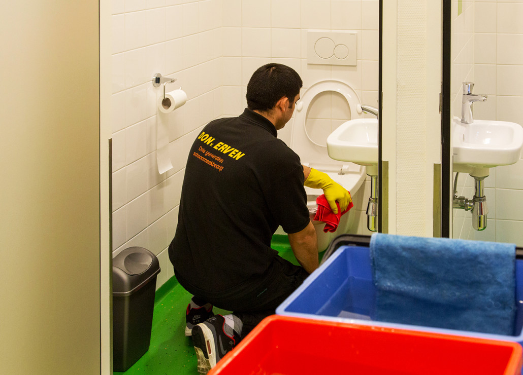 Werknemer die een toilet schoonmaakt